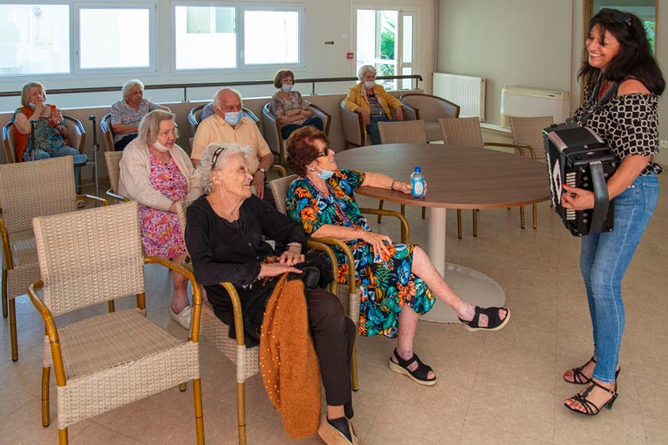 11femmes seniors souriantes dans le salon de la maison de retraite La Constance avec une accordéoniste - Photo © Aurélien Meimaris