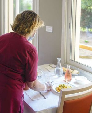 11Femme de dos servant une table au restaurant de la maison de retraite à Marseille La Constance