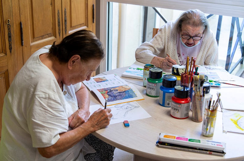 Art-Thérapie pour personnes âgées à la Constance Résidence Seniors Marseille. Photo de 2 dames dessinant à une table