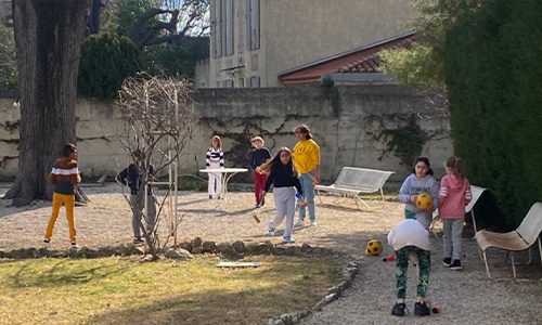 Photo d'enfants jouant au ballon avec des seniors dans le jardin de La Constance