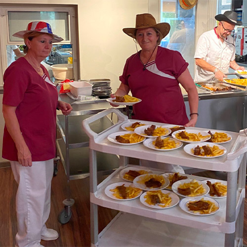 Photo de 2 membres de l'équipe au restaurant de la maison de retraite à Marseille La Constance avec un chariot de plats lors de la fête nationale américaine